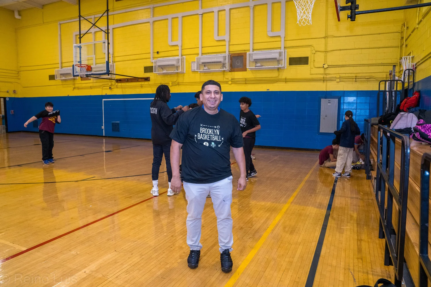 Coach smiling in gym during Brooklyn Basketball school visit