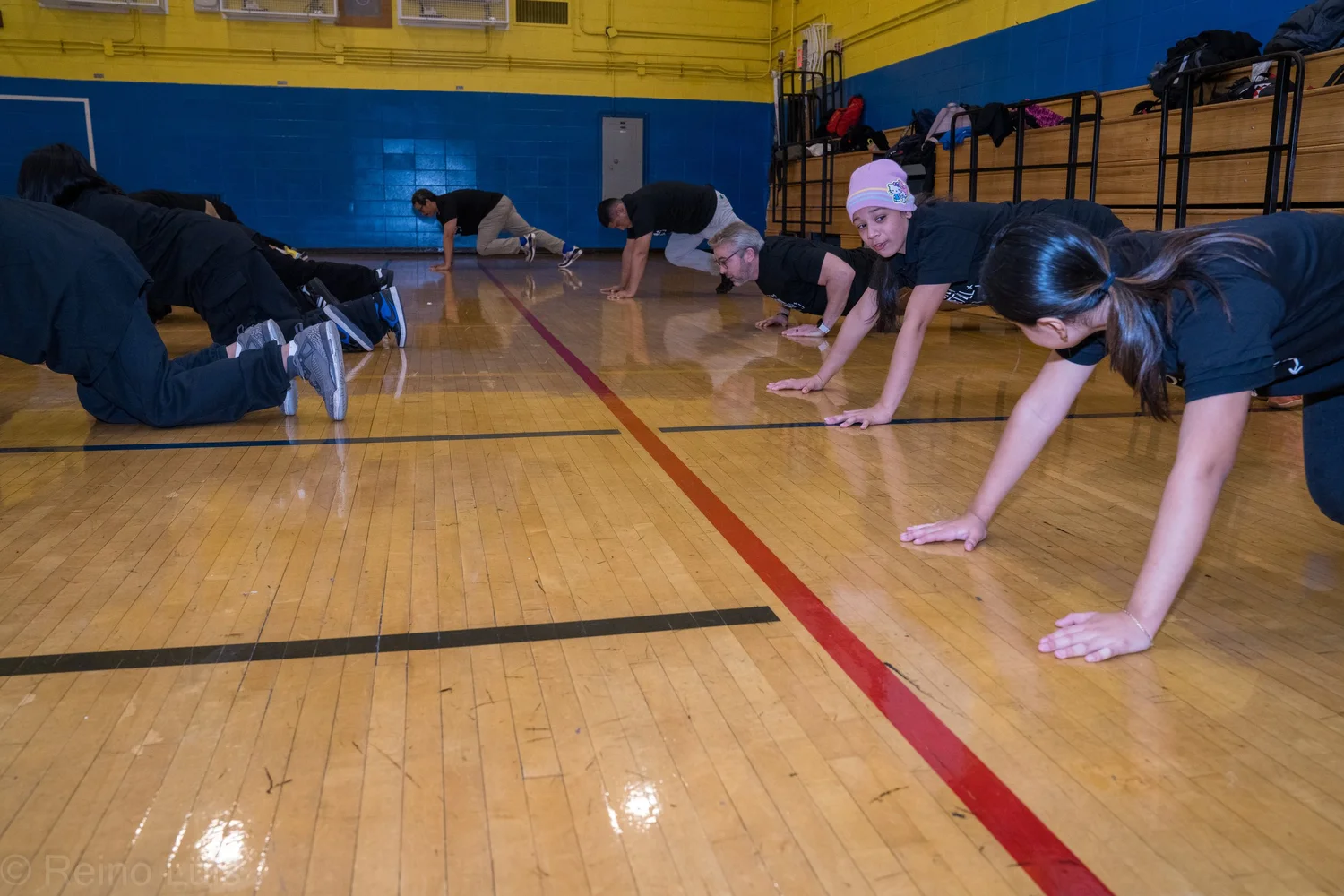 Students and adults doing push-ups together in a school gymnasium