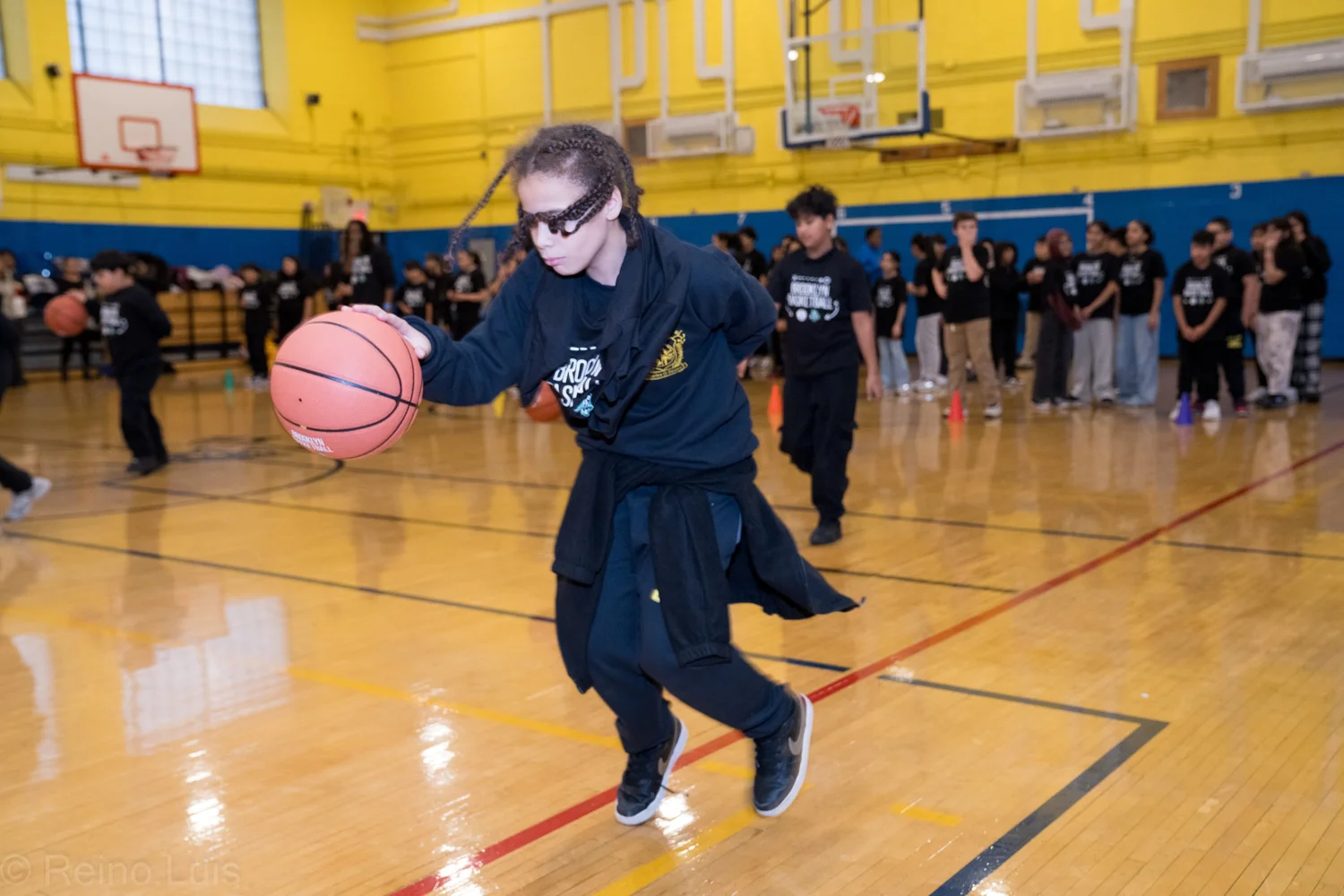 Student dribbling basketball during gym class drill at MS 136