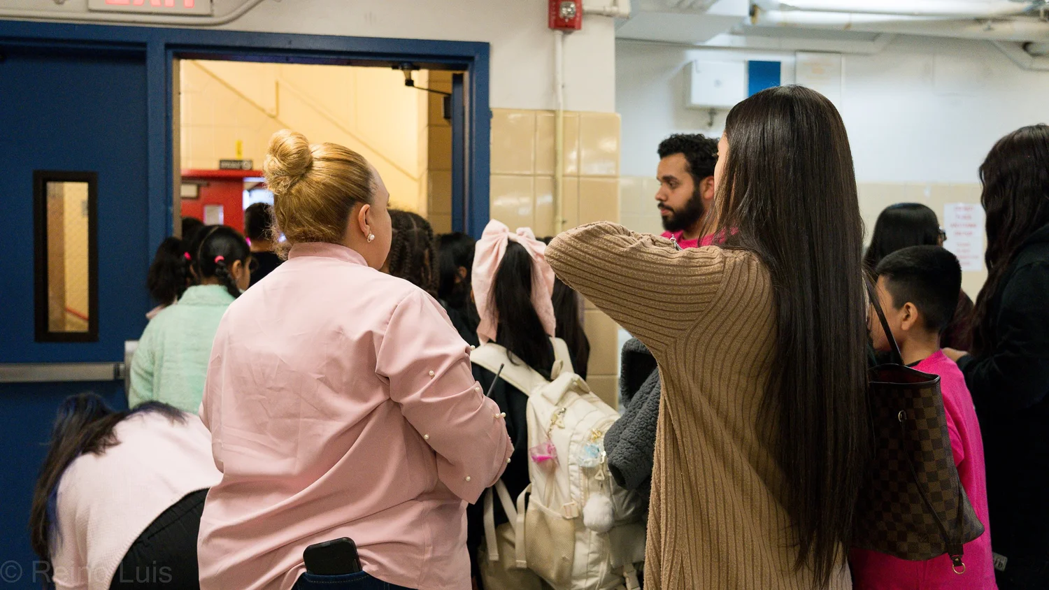Families and students entering school building through hallway doors