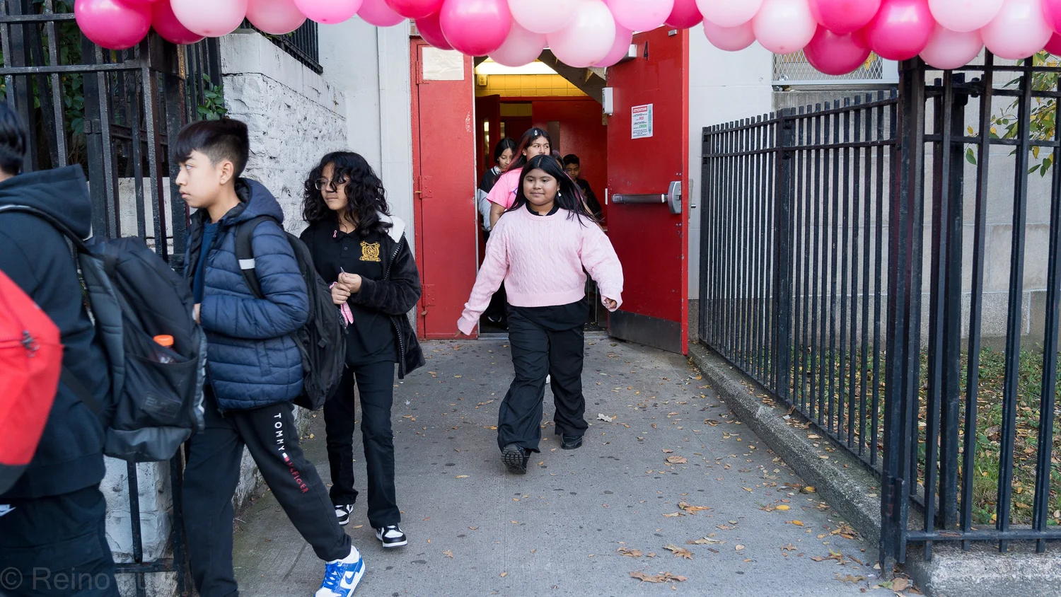 Students exiting school through pink balloon decorated doorway