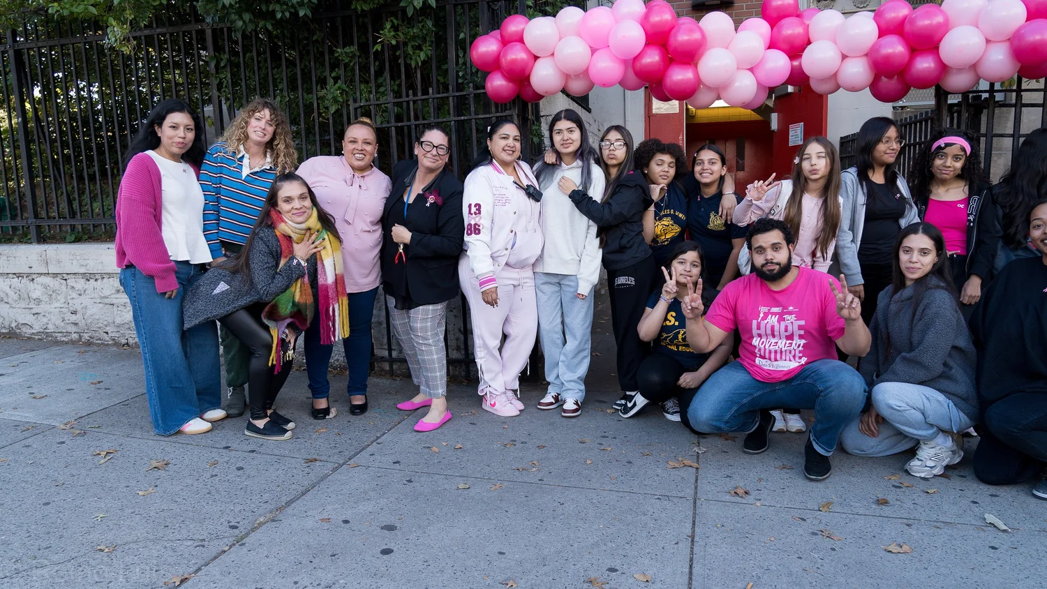 Students and staff pose under pink balloon arch at school event