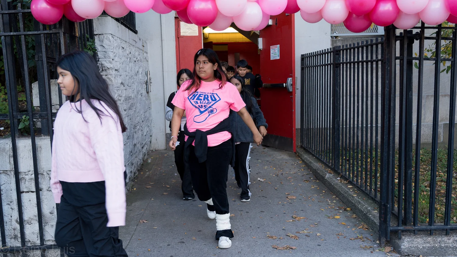 Students walking through pink balloon arch at school event