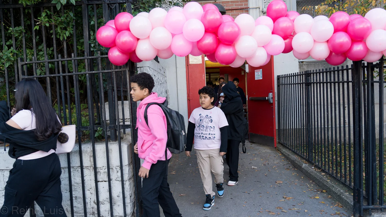 Students entering school through pink and white balloon arch