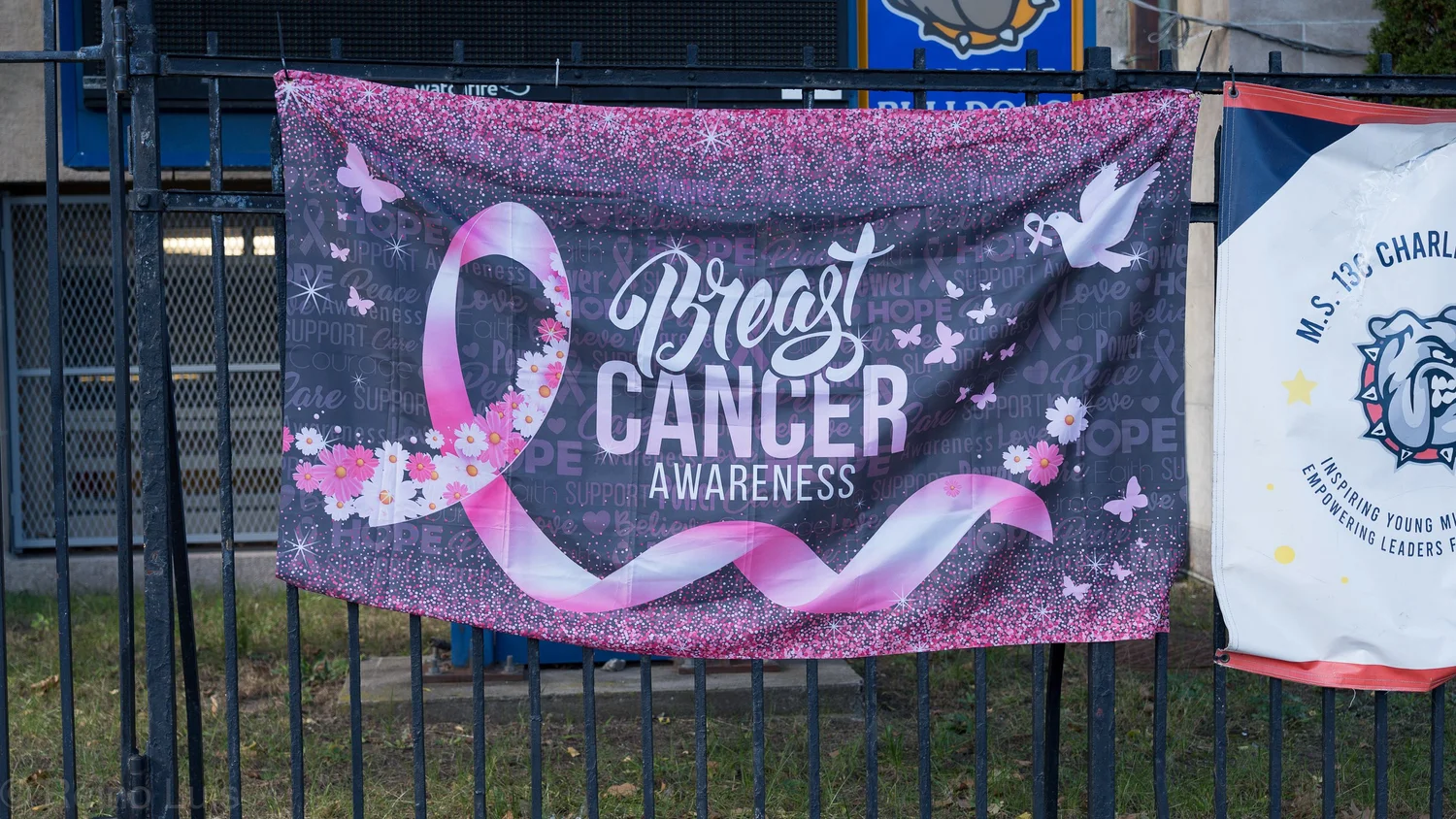 Breast Cancer Awareness banner hanging on school fence