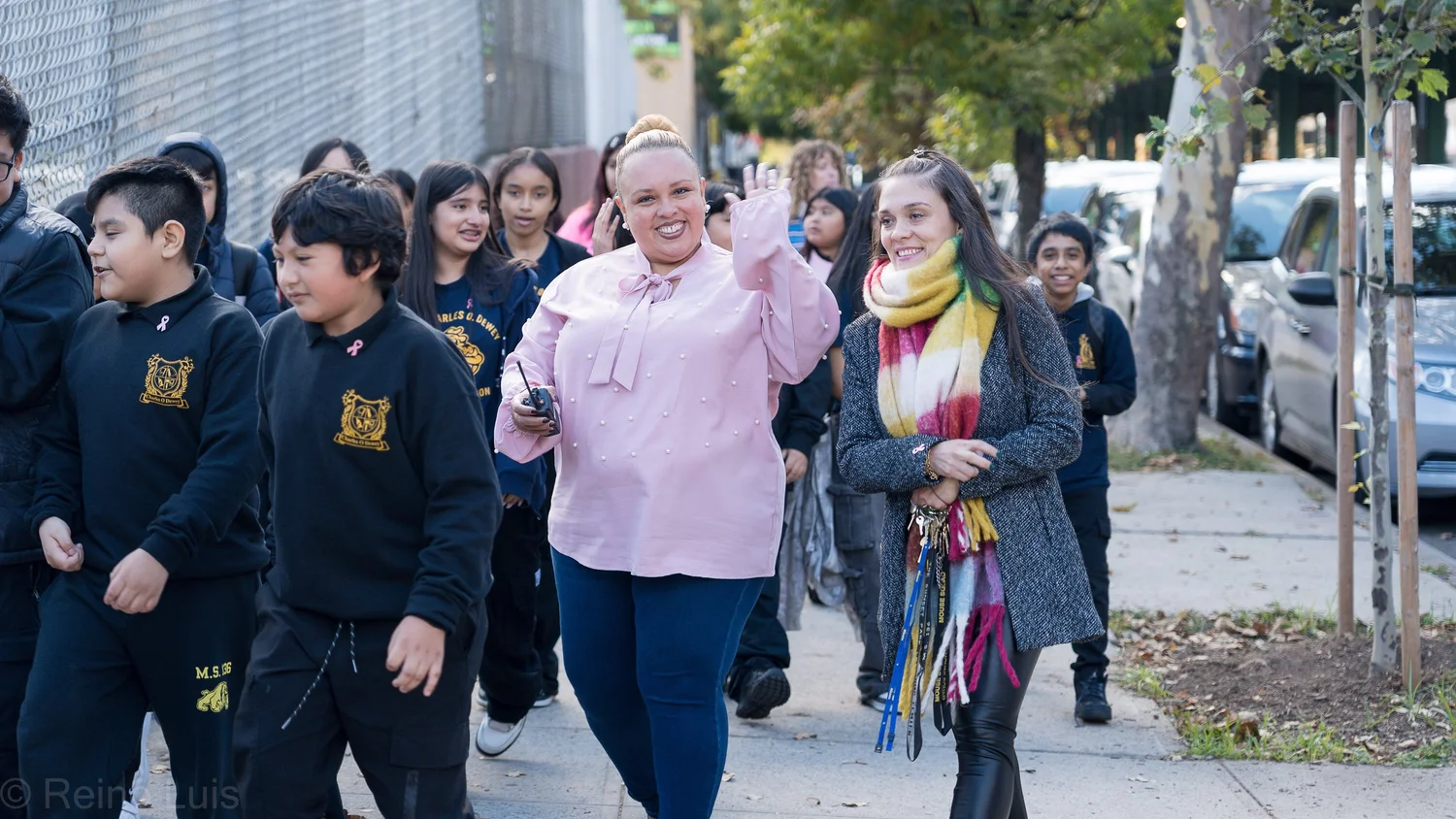 Two staff members lead smiling students on an outdoor school walk