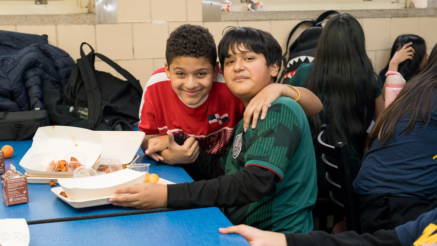 Two middle school students smiling together during lunch in cafeteria