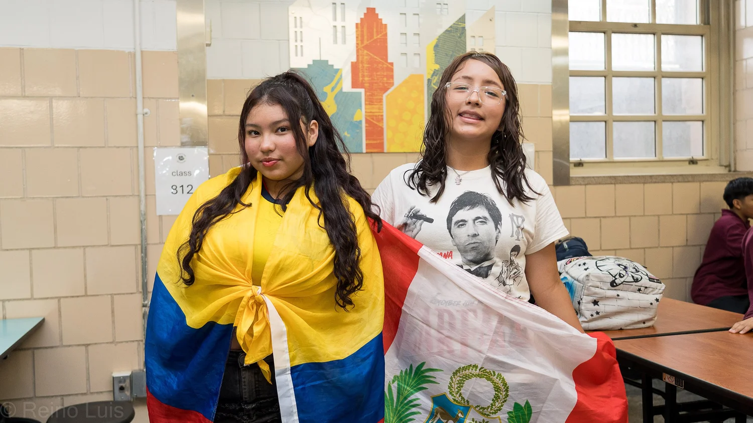 Two students proudly displaying Colombian and Peruvian flags in school cafeteria