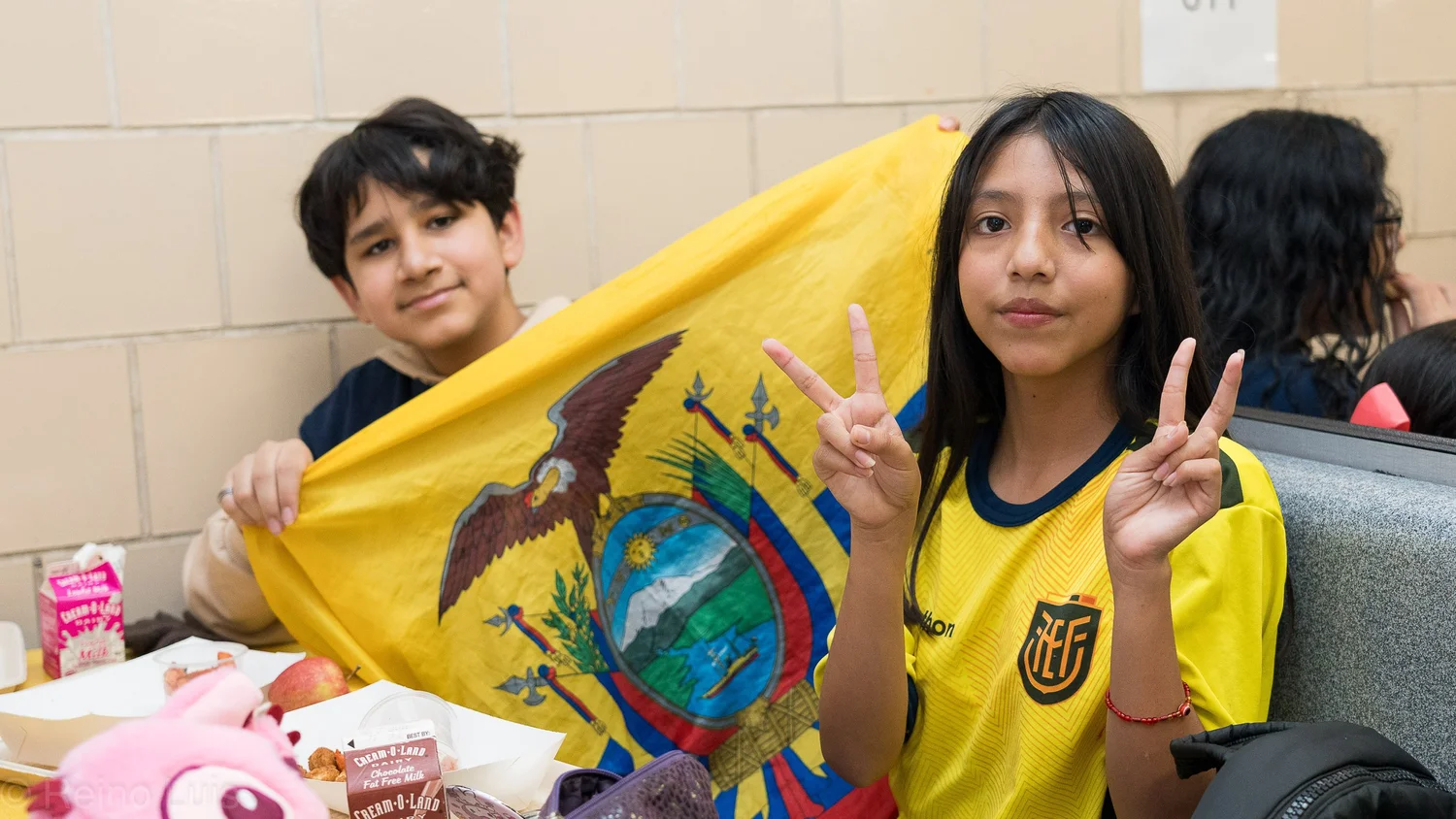 Two students proudly displaying the Ecuadorian flag at lunch