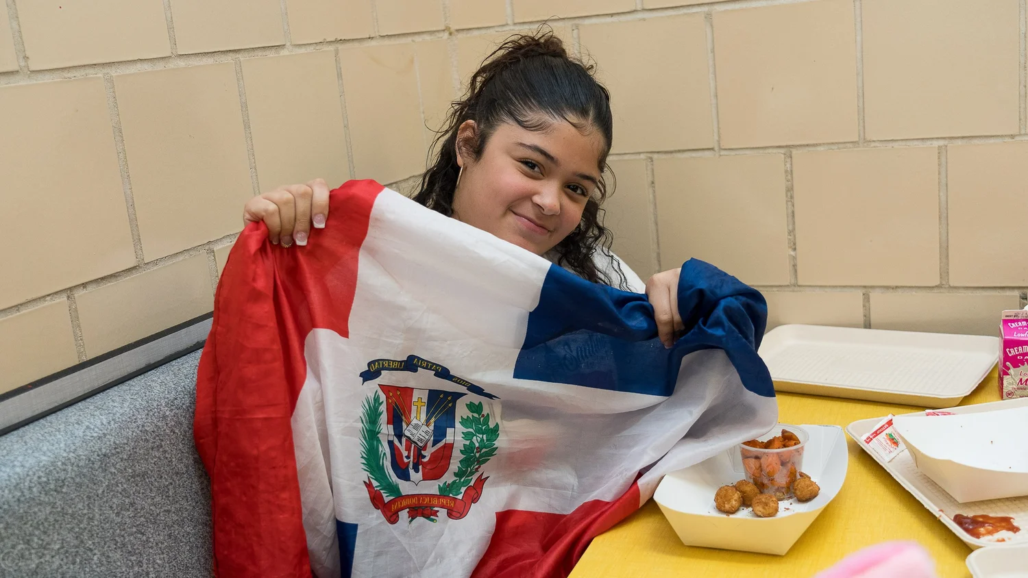 Student smiling while holding a Dominican Republic flag at school