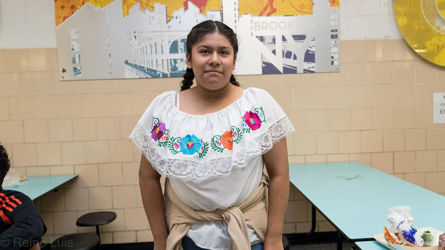 Student wearing traditional embroidered Mexican blouse in school cafeteria