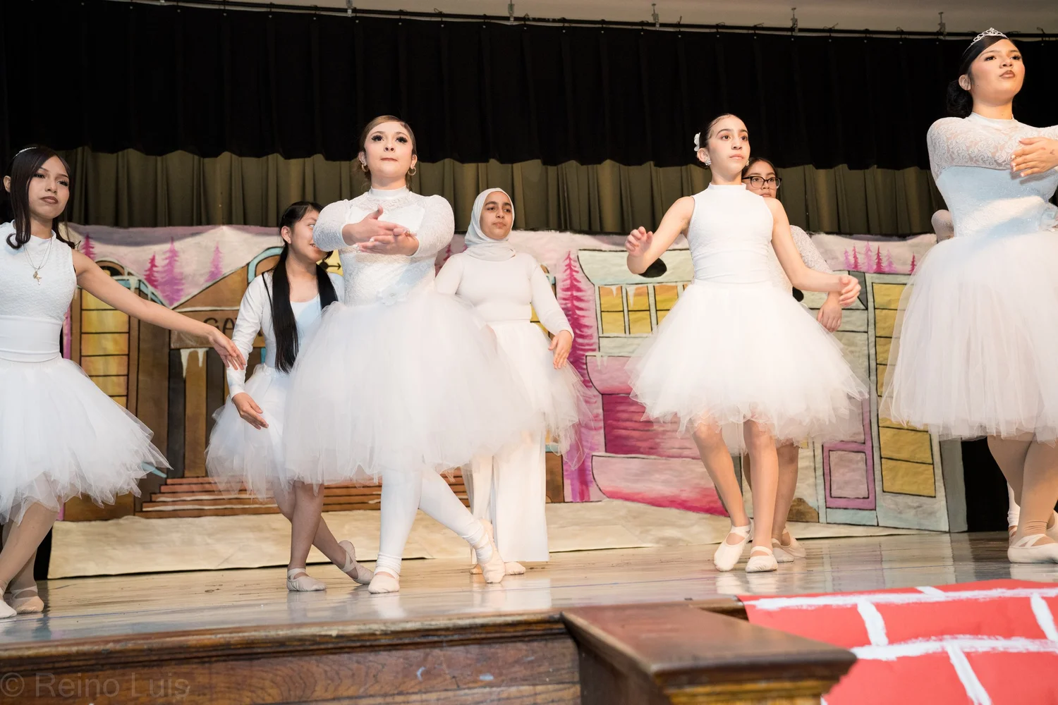 Students performing ballet in white tutus on school stage