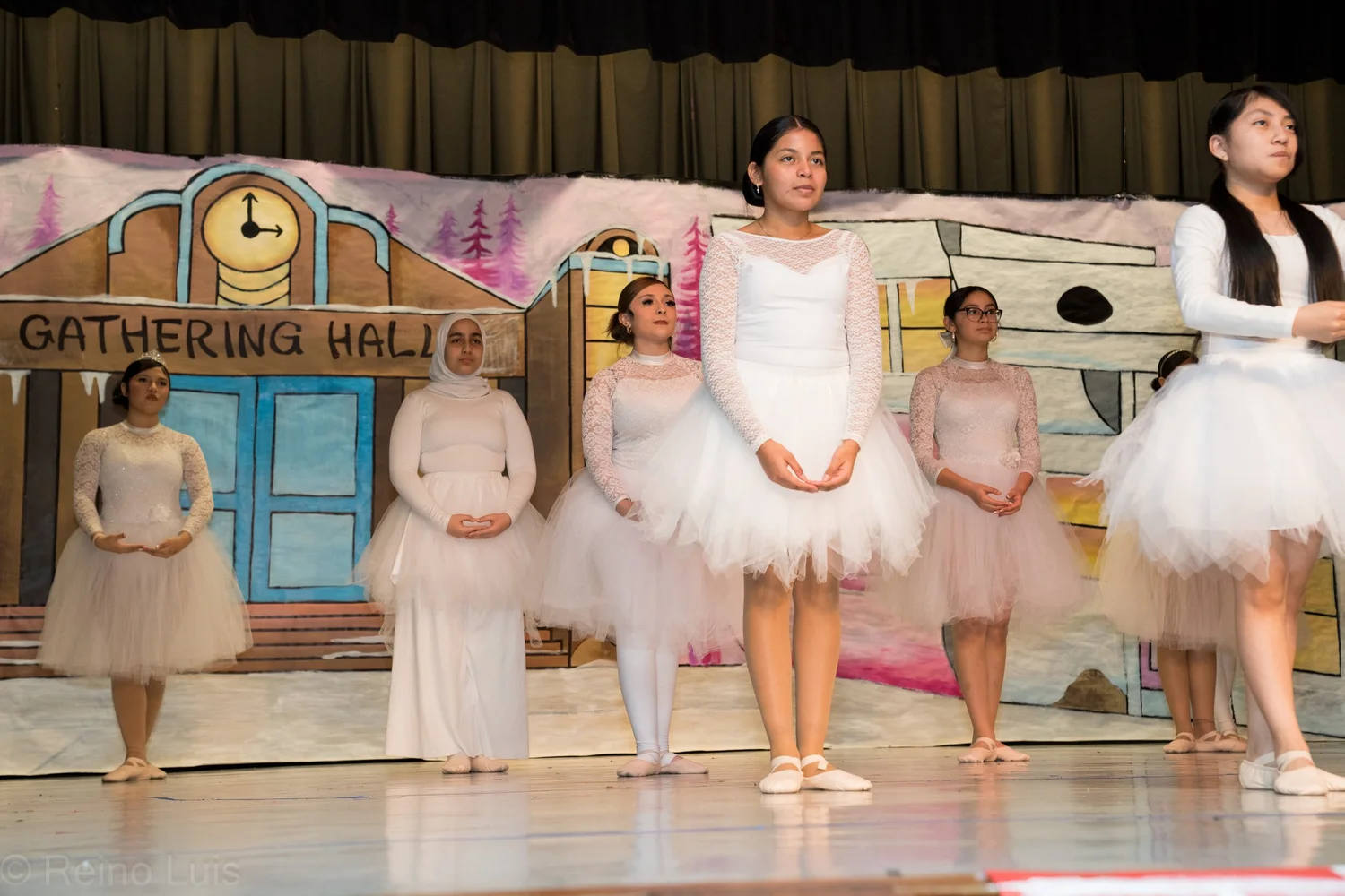 Students performing ballet on stage in white tutus during school show