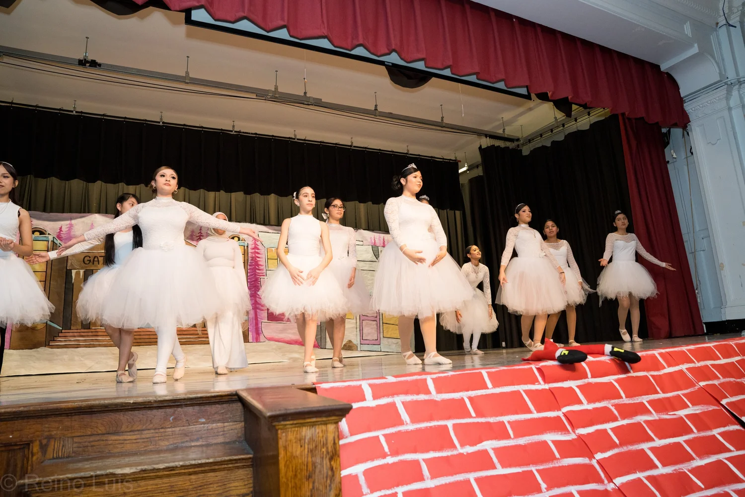 Students performing ballet in white tutus on school stage