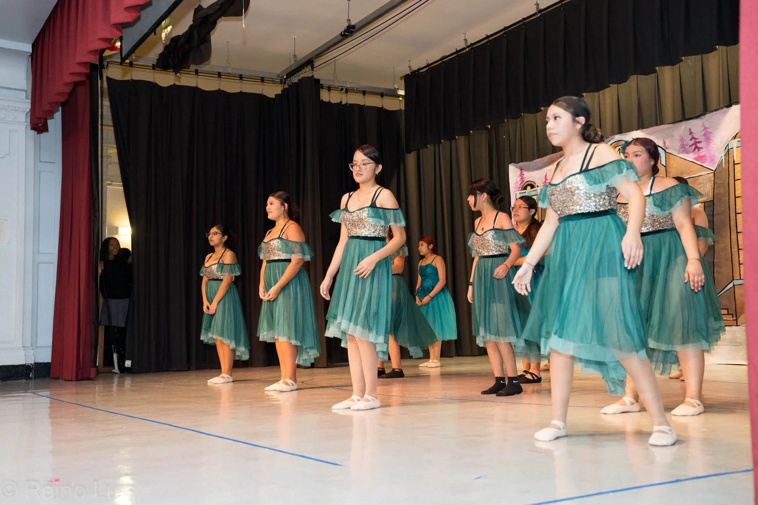 Students performing on stage in matching teal dance costumes