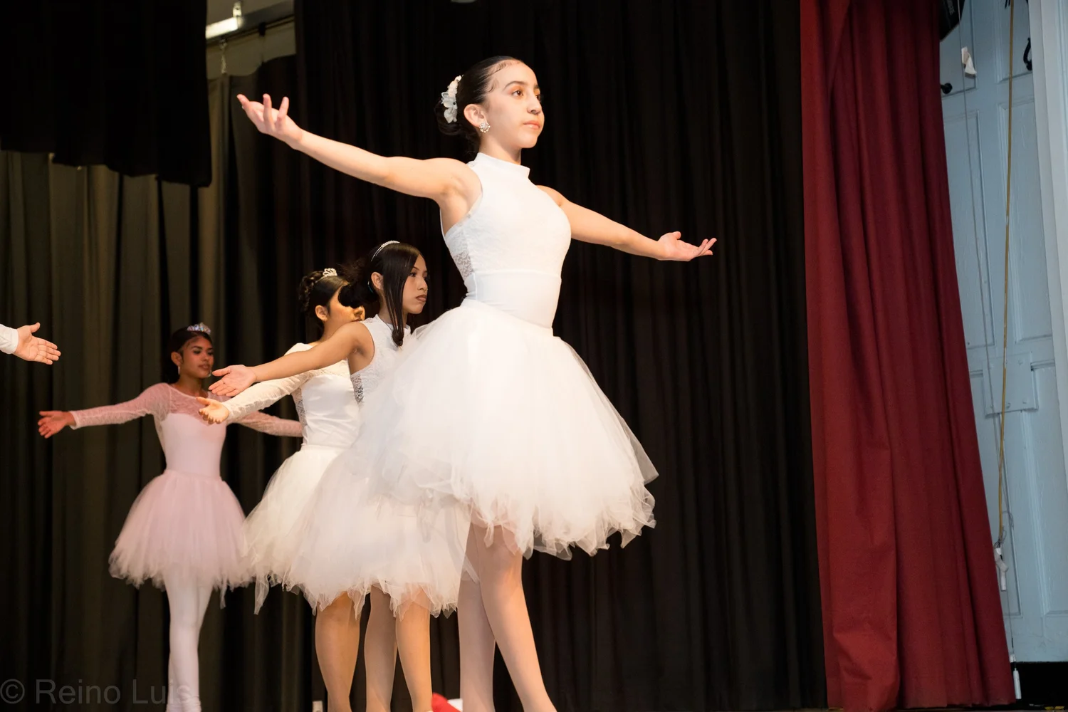 Student ballet dancers performing on stage in white tutus