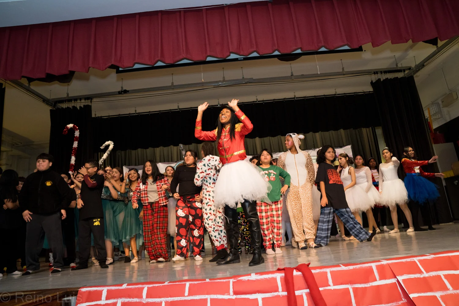 Students performing in a holiday stage production in festive costumes