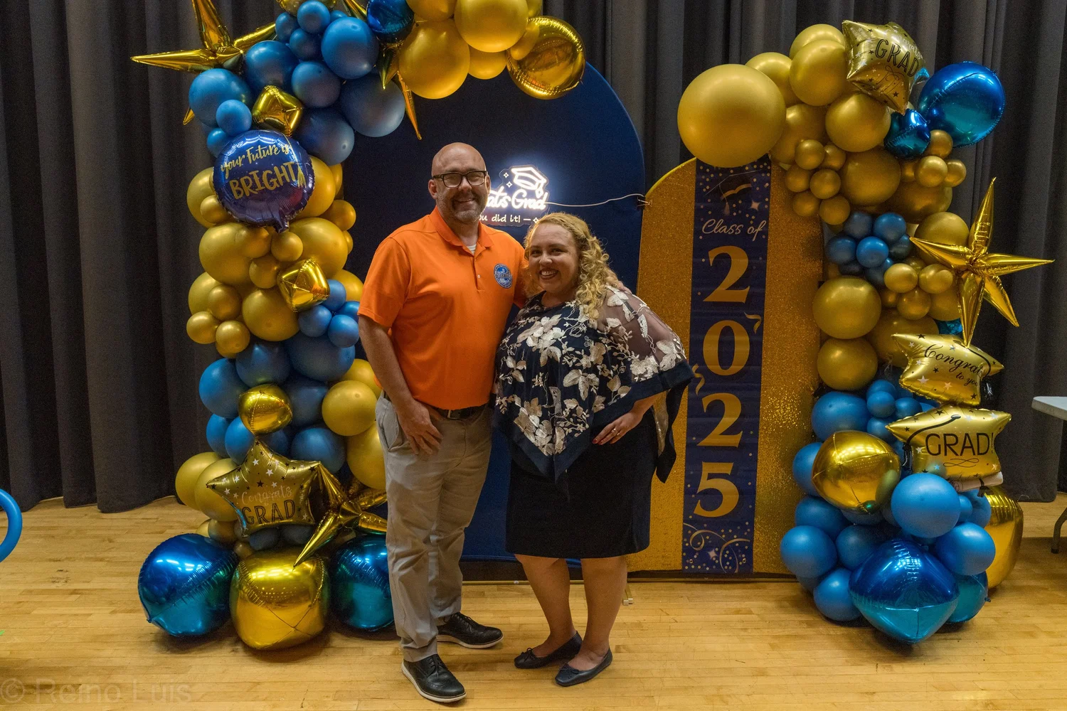 Two adults posing at Class of 2025 graduation photo backdrop