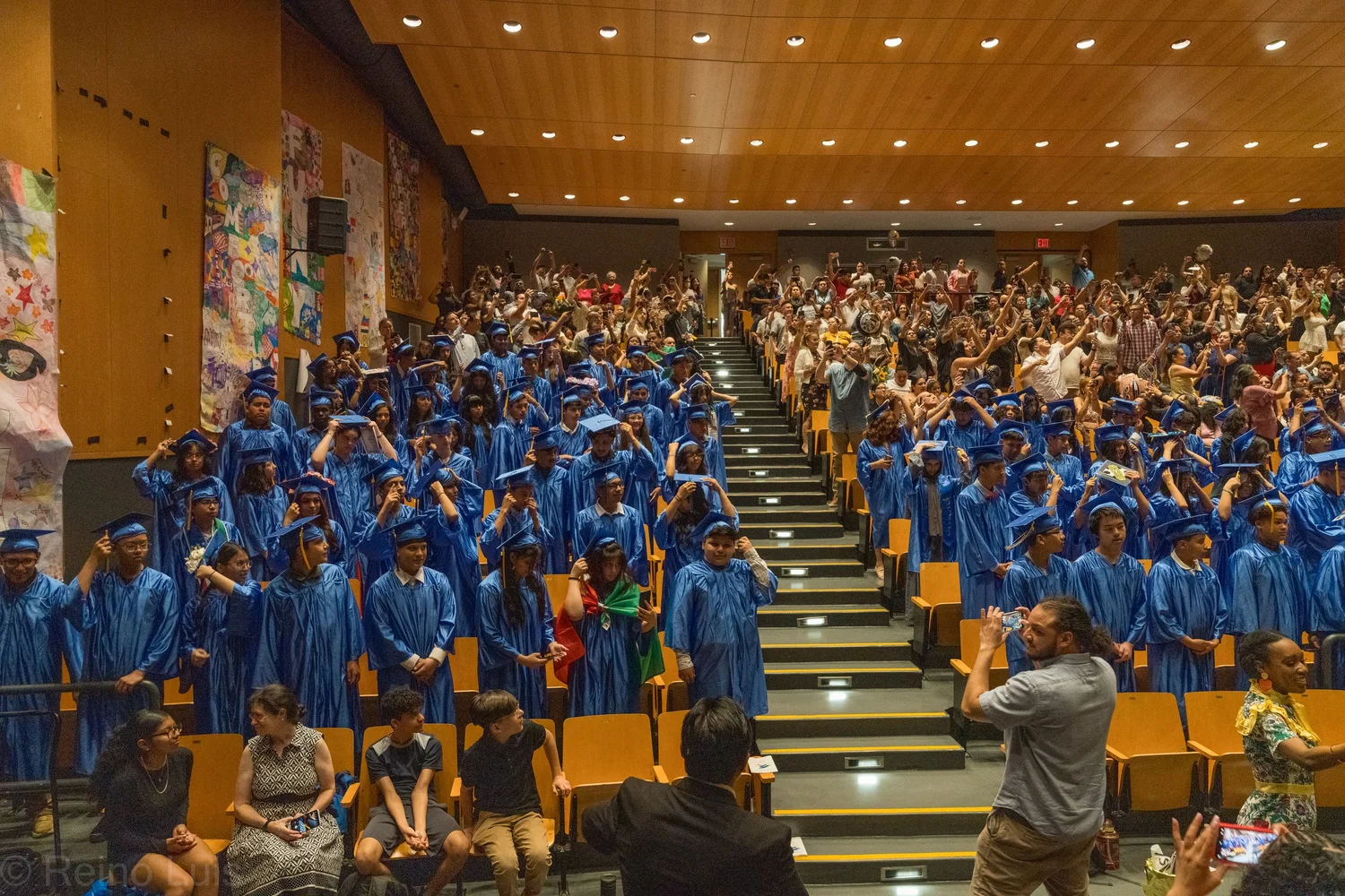 Students in blue caps and gowns celebrate at school graduation ceremony