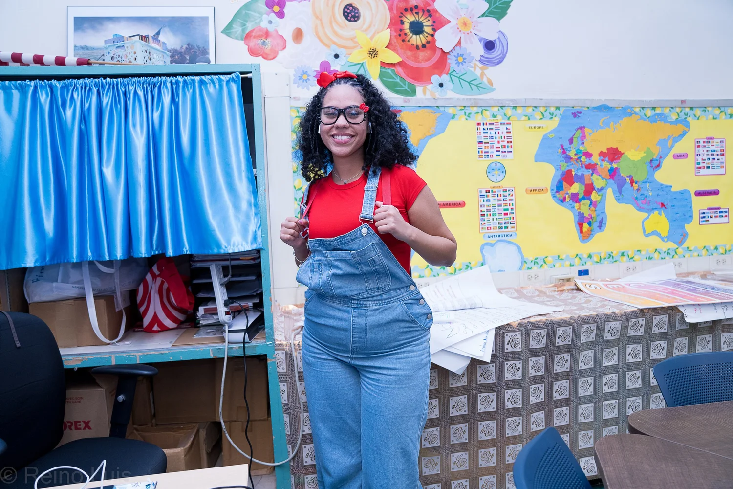 Smiling teacher in overalls standing in decorated classroom