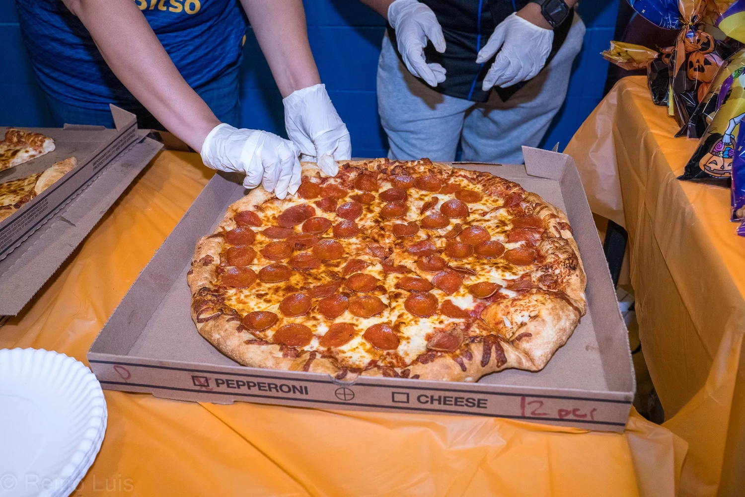 Volunteer serving pepperoni pizza at a school event