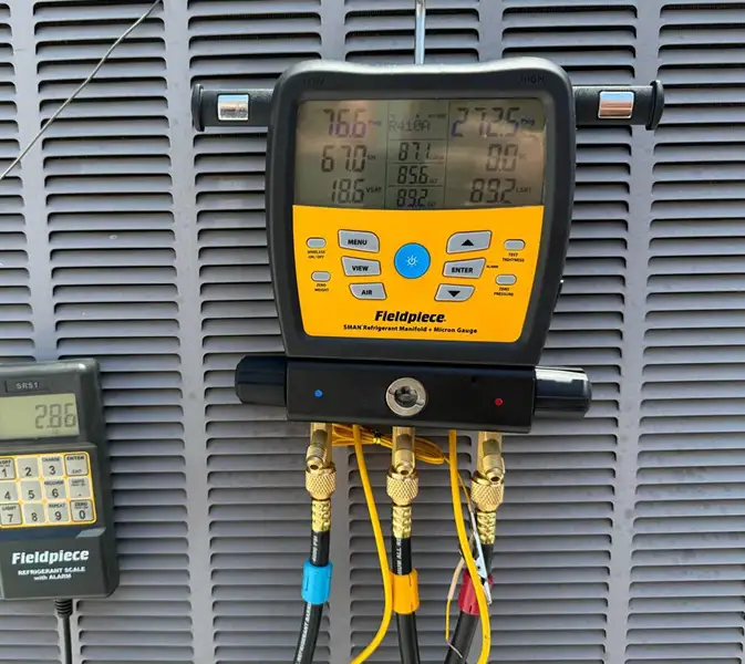 HVAC digital manifold gauge connected to an outdoor AC unit during diagnostics