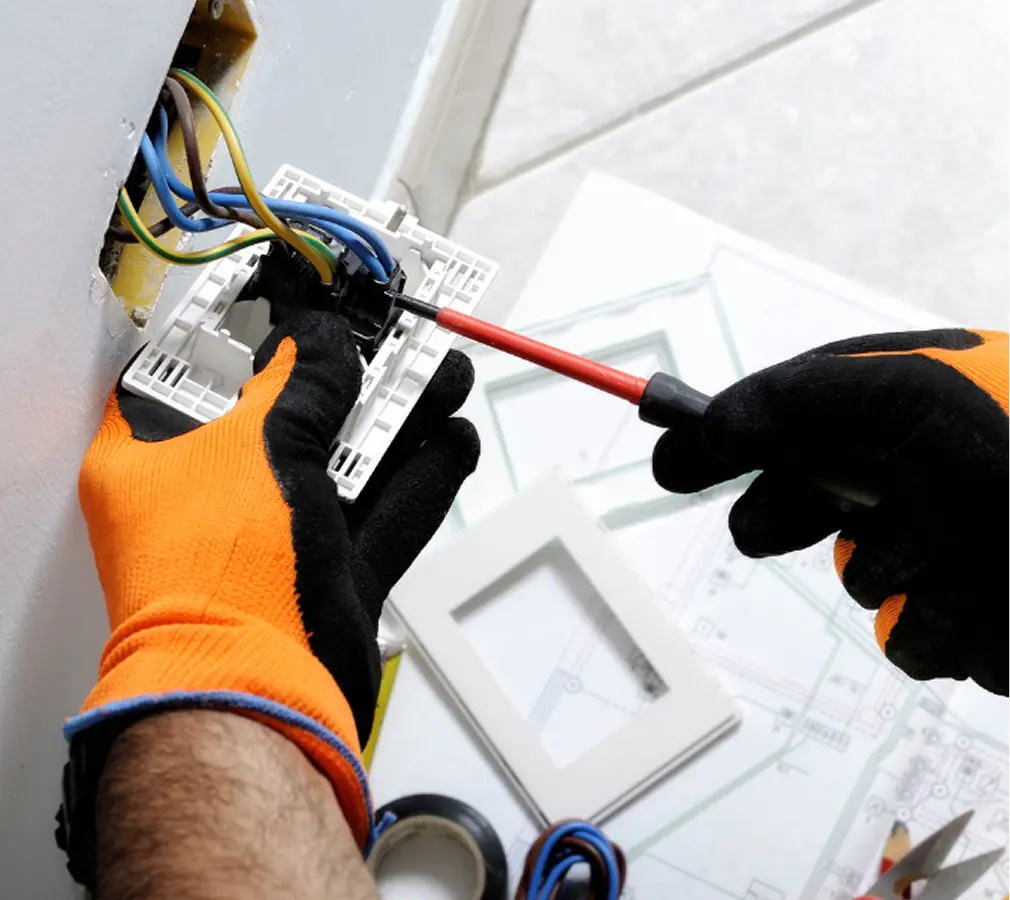 Electrician installing electrical outlet wiring with screwdriver.