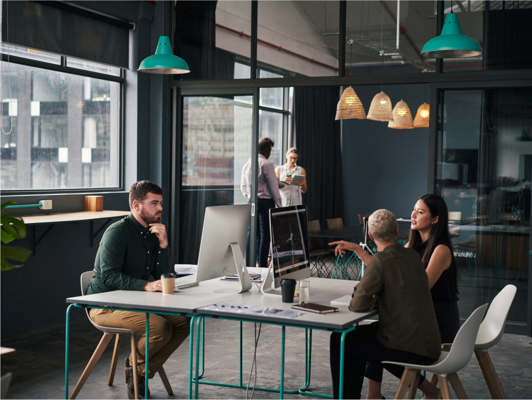 Modern coworking office space with diverse team collaborating at computers.