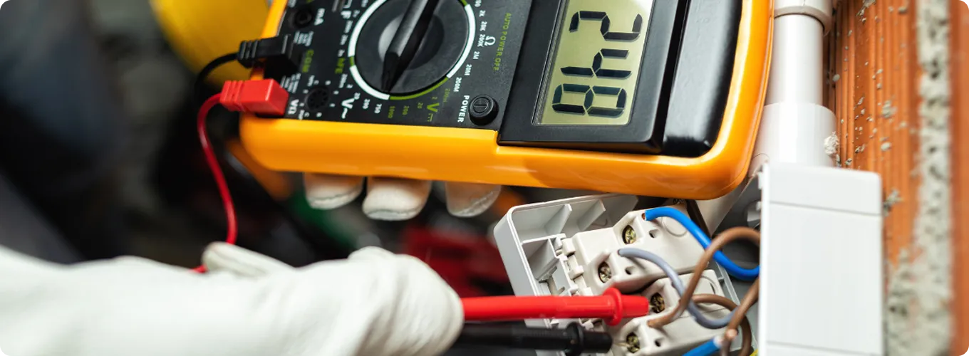 Electrician using a multimeter to test electrical wiring connections.