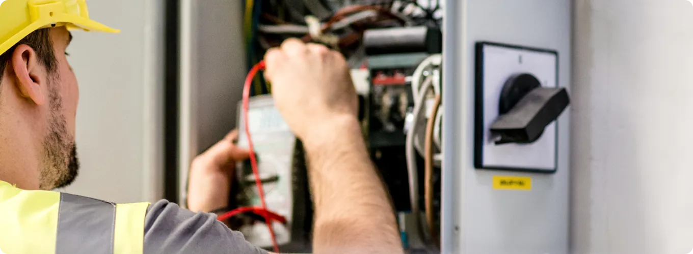 Electrician testing wires inside an electrical panel.