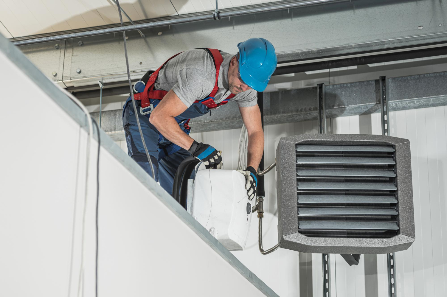 Professional technician installing indoor HVAC heating unit in commercial building