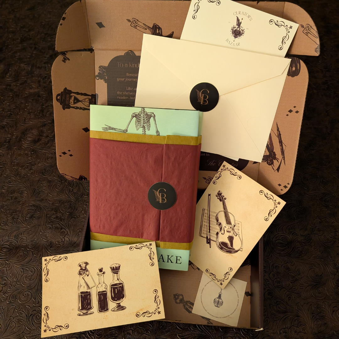 The Curator's Bazaar subscription box opened to display a wrapped book, a sealed letter, stationary for drinks and music, and small perfume card