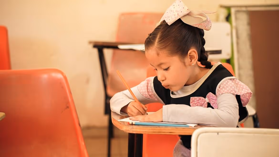 kid girl writing on paper with pencil