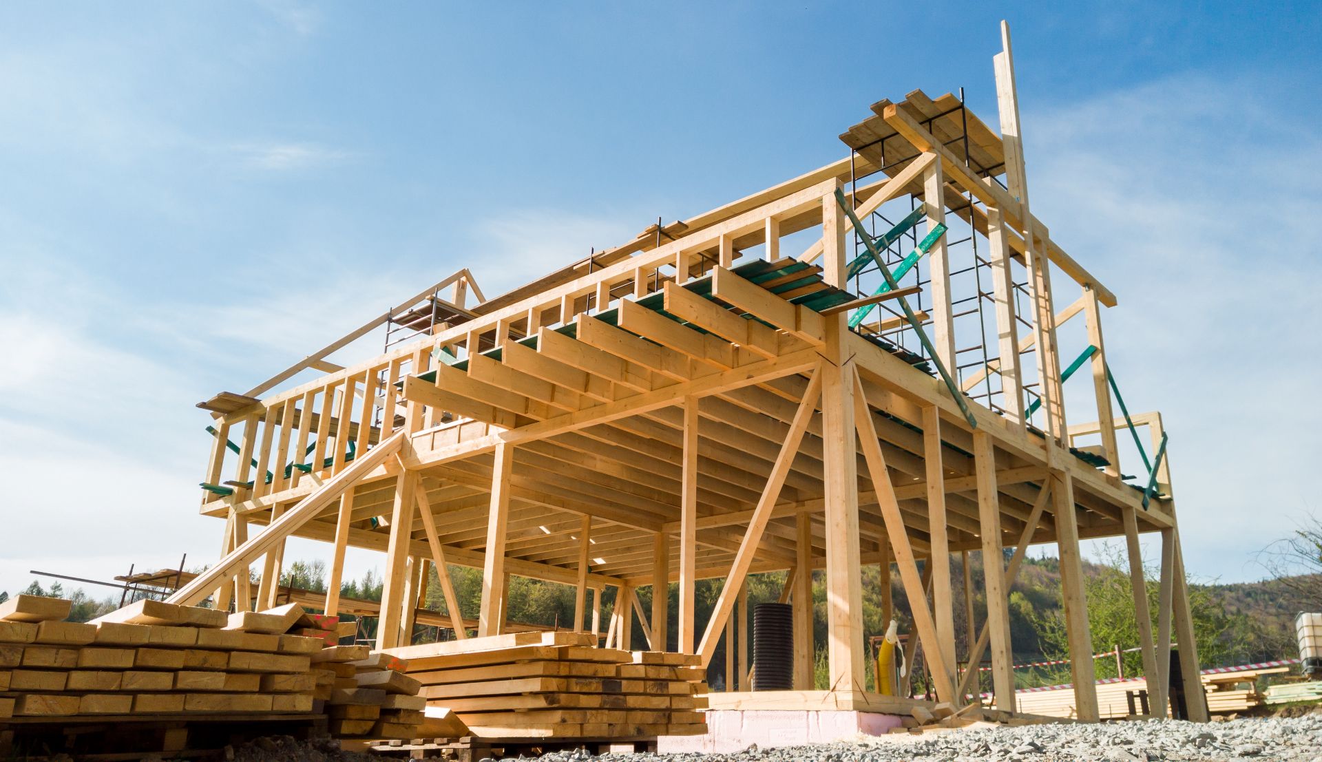 Framing of a new home under construction with scaffolding and materials on-site.