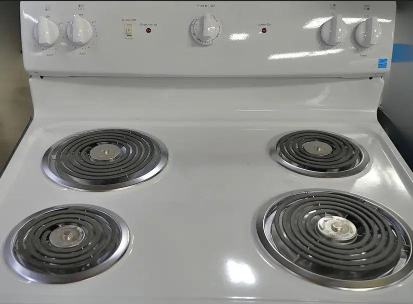 White electric coil-top stove with four burners and control knobs on the back panel.