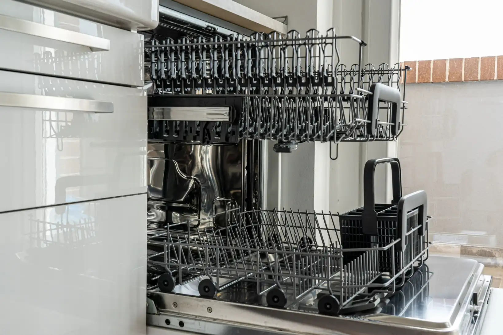 Open dishwasher with empty racks and utensil holder