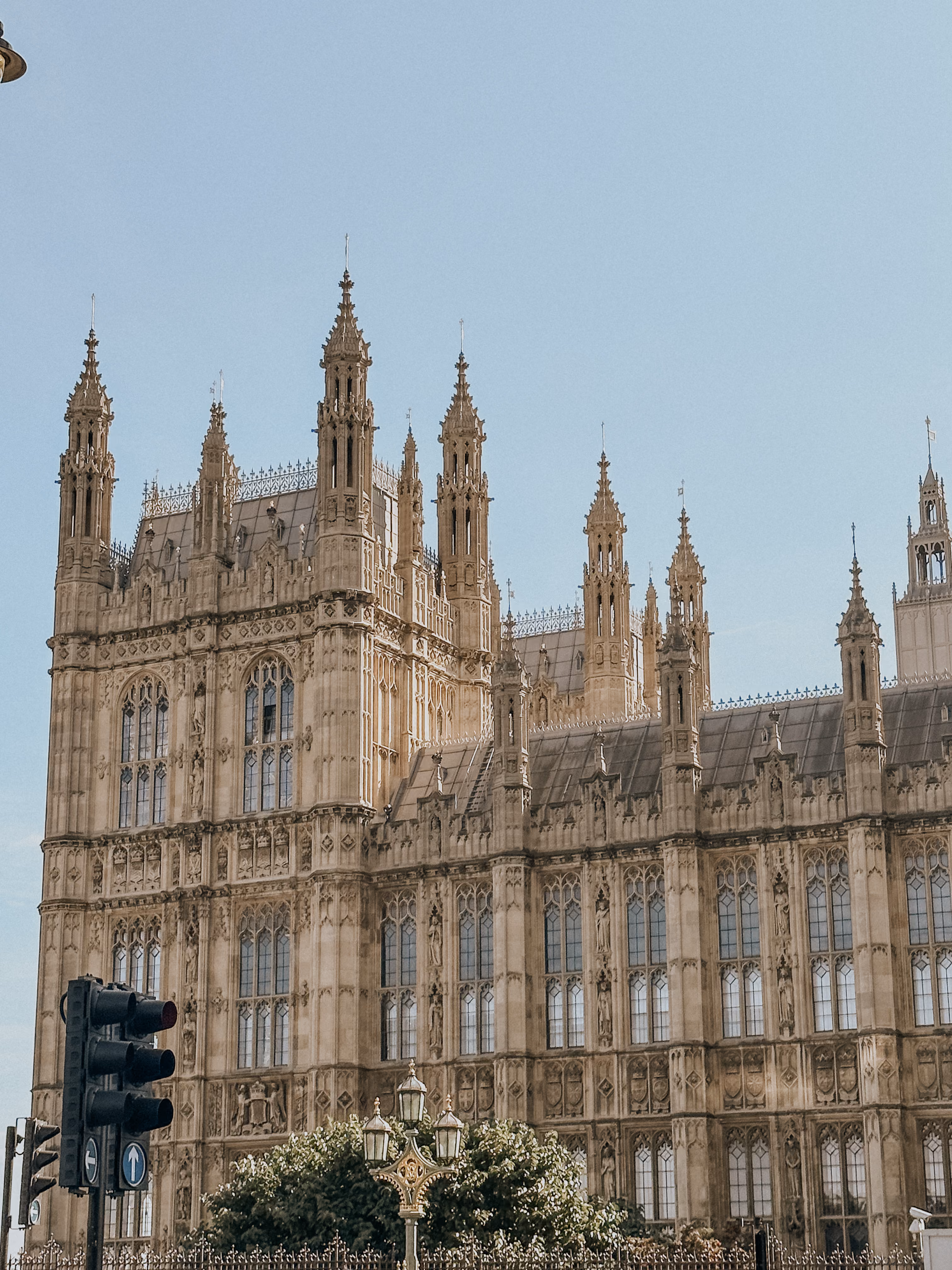 Historic Gothic-style building with tall spires and detailed stonework under a clear sky.