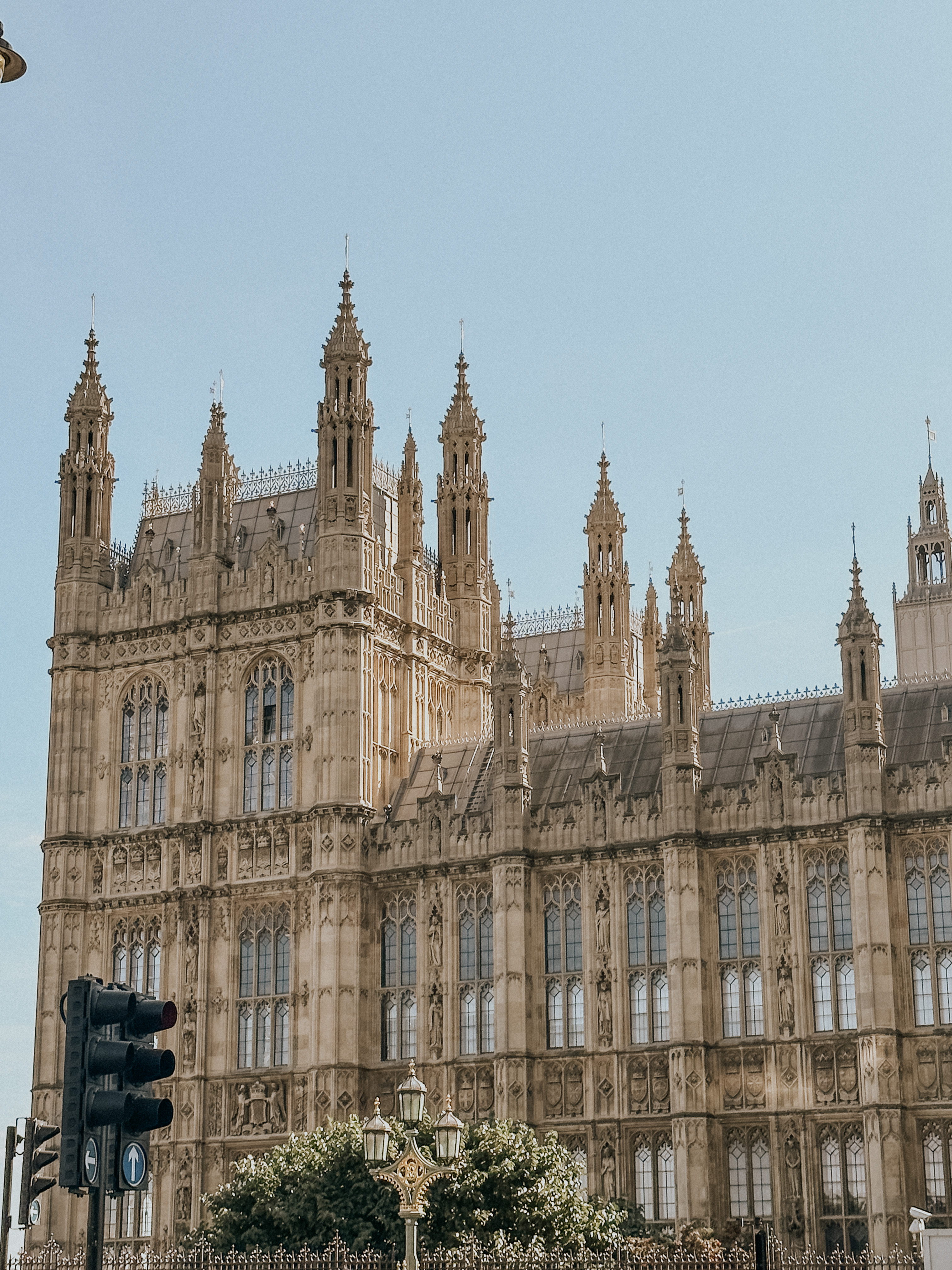 Historic Gothic-style building with tall spires and detailed stonework under a clear sky.