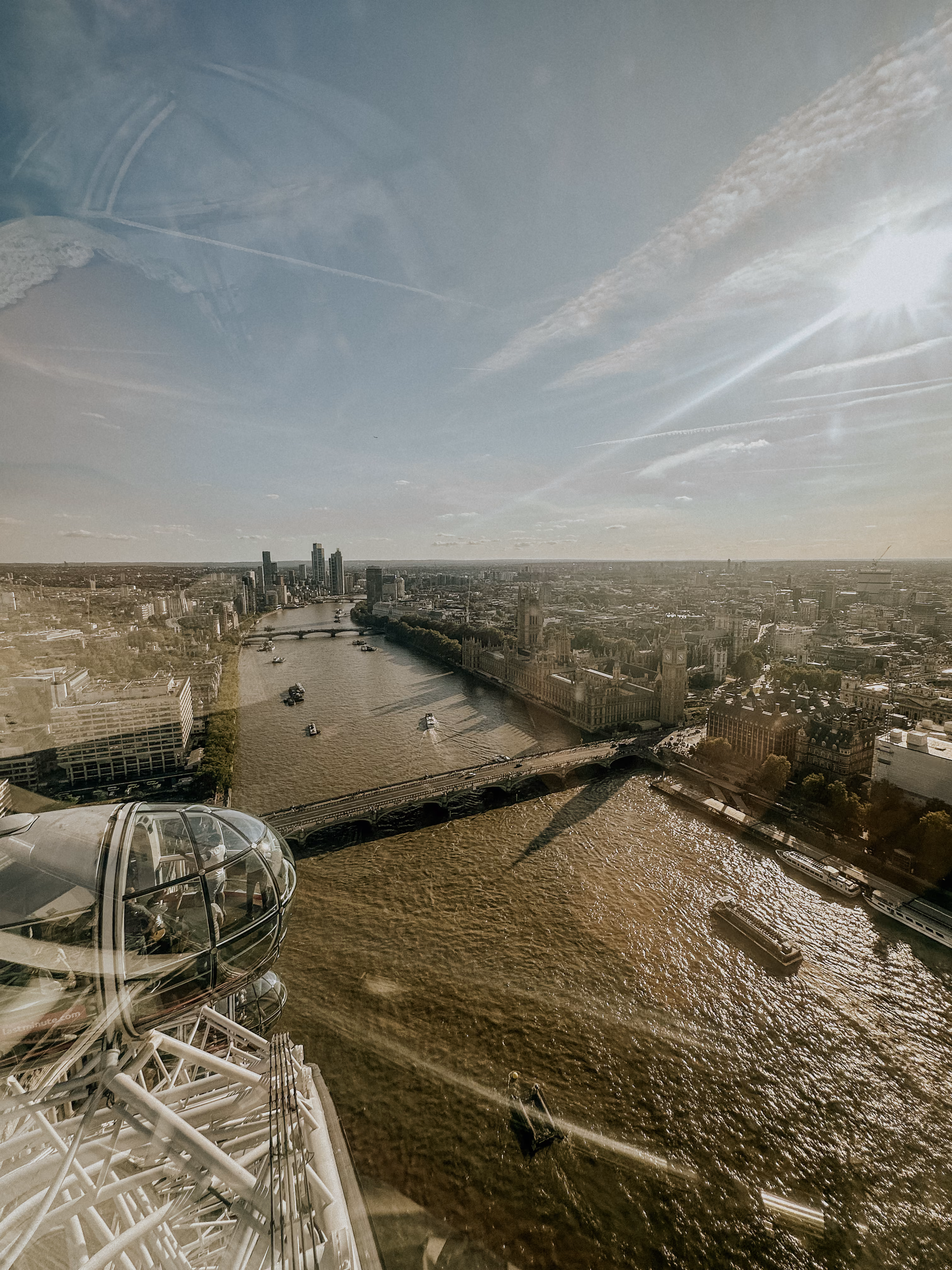 View of the River Thames, London Eye pod, Westminster Bridge, and Big Ben on a sunny day.
