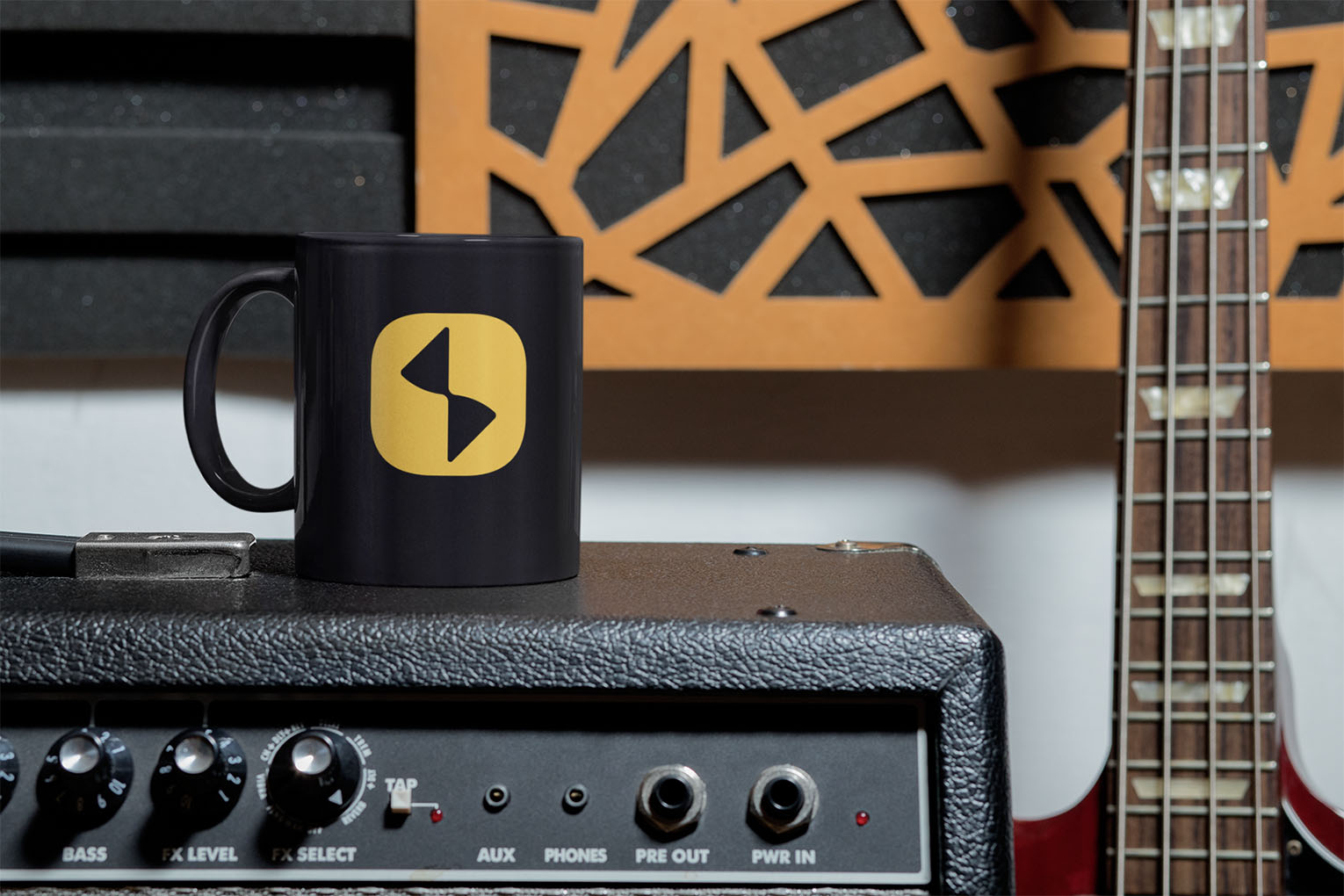 Studio 81 Productions branded coffee mug with yellow icon print sitting on guitar amplifier in home studio environment