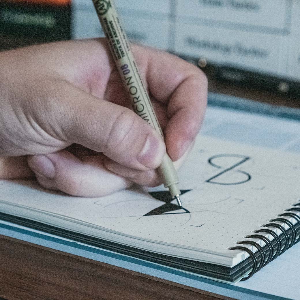 Brand designer finalizing logo concept sketch with pen in notebook during creative process
