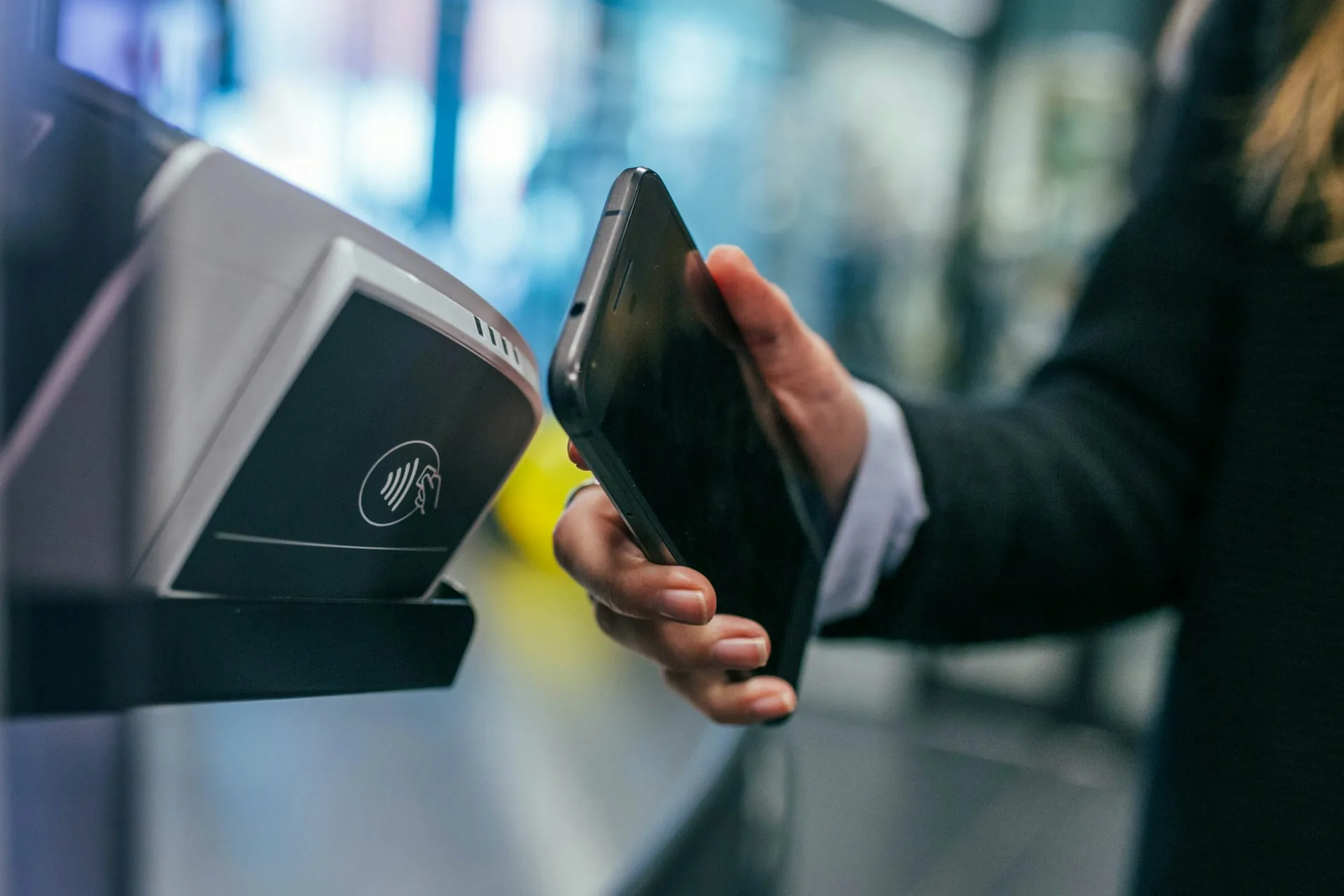 Hand tapping a phone against a contactless card reader to pay in store