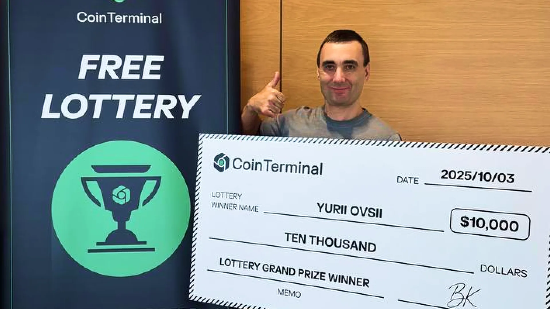 Lottery winner Yurii Ovsii holding an oversized $10,000 CoinTerminal prize cheque