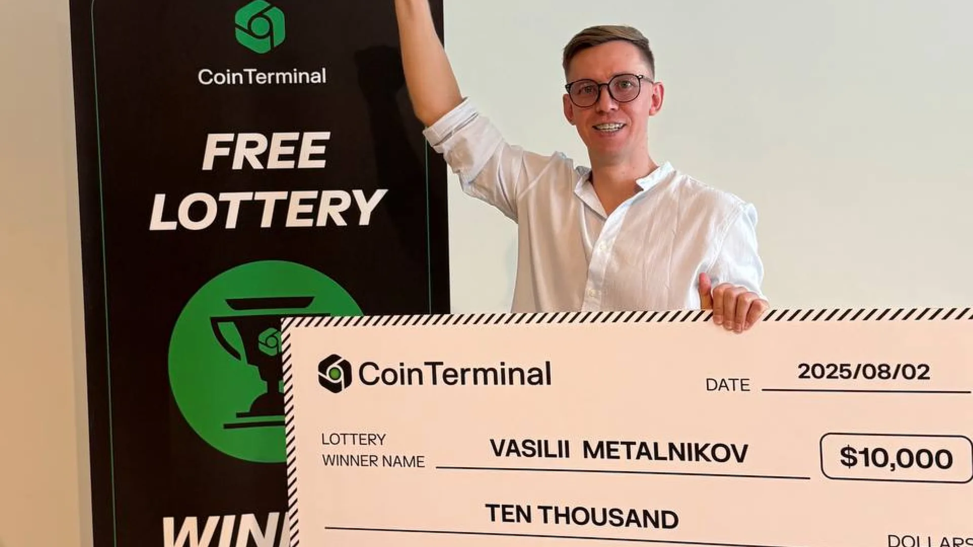 Lottery winner Vasilii Metalnikov holding an oversized $10,000 CoinTerminal prize cheque