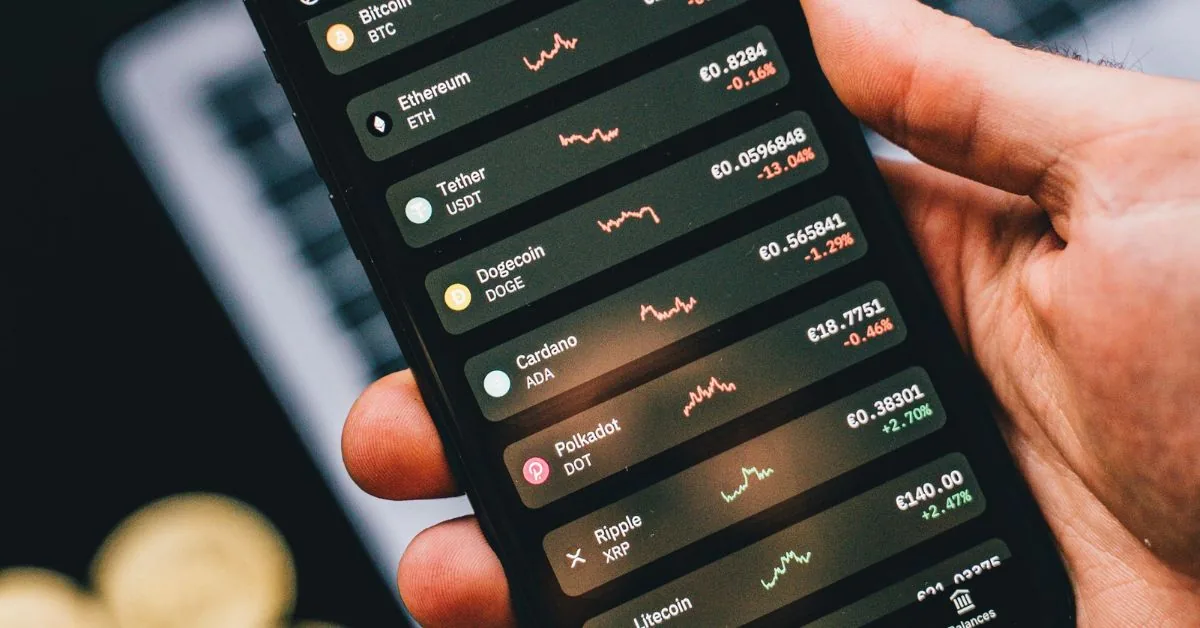 Hand holding a phone showing a crypto watchlist with Ethereum, Tether, Dogecoin and Cardano prices