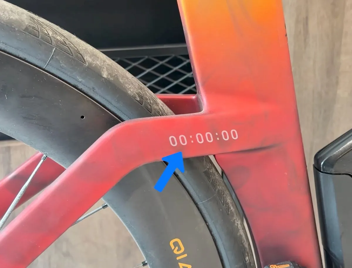 Trek Speed Concept SL7 rear triangle showing minimal clearance between 32mm tyre and chainstay junction, blue arrow pointing to tight gap near "00:00:00" frame detail