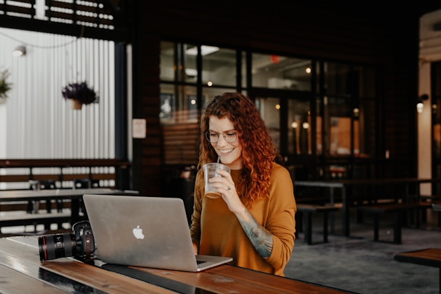 Business owner in brown long sleeve shirt sitting by table using macbook