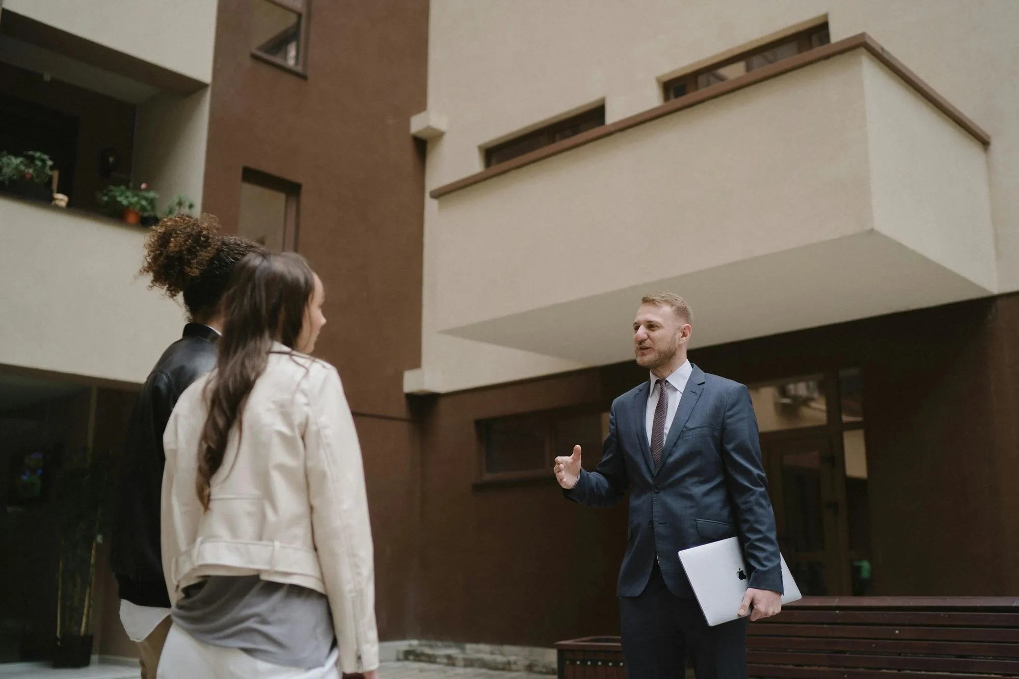 Property managers and clients outside an apartment building, representing real estate bookkeeping and lease support