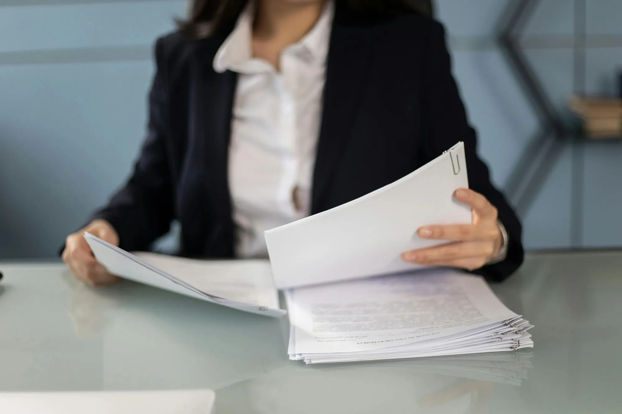 Person reviewing paperwork and financial reports, representing support for recruiters, consultants, and legal firms