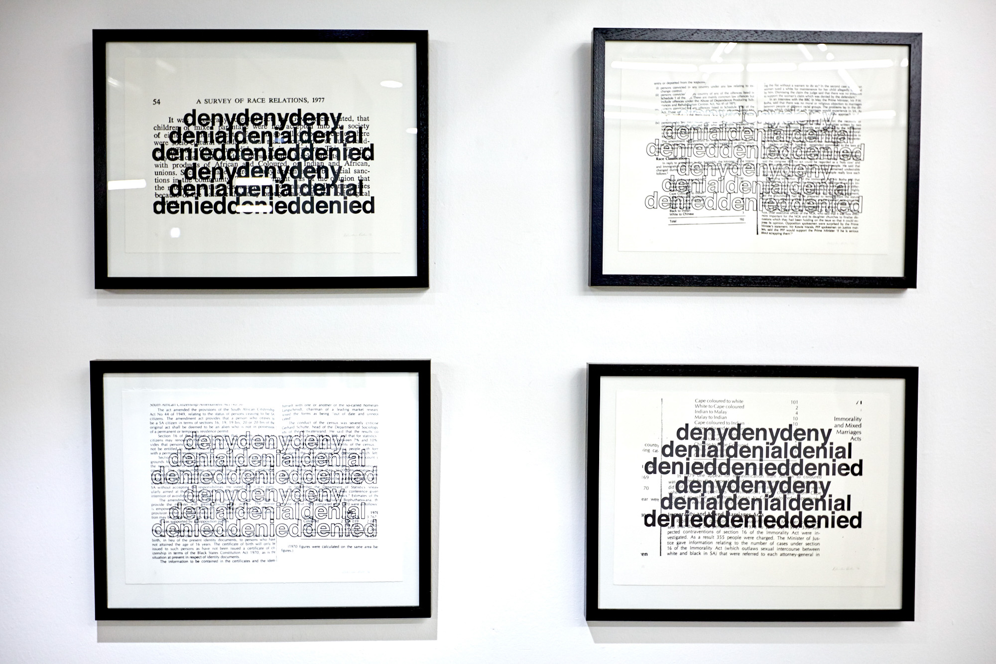 Four black-framed screenprints layering the repeated words "deny, denial, denied" in bold black type over pages from A Survey of Race Relations, 1977 and other apartheid-era texts about race classification and the Immorality Act.
